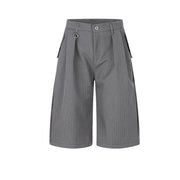 A pair of gray pinstriped shorts with a unique wide-leg silhouette, featuring pleats at the front, side pockets, and a metal ring detail on the waistband, shown against a plain white background.